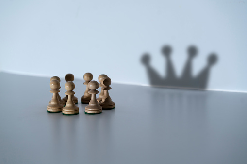 abstract concept, chess pawns make a shadow of queen or king crown