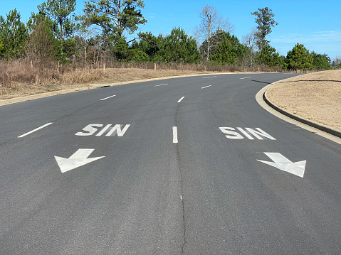 Two sin signs on road in curve with directional arrows pointing down