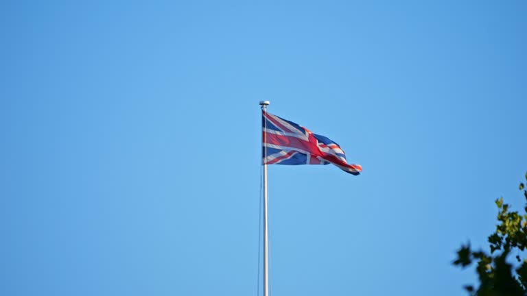 The big national flag of the United Kingdom. British flag flying in the wind, in the sun. Slow Motion. Sharp winds. The flag gently tattered. 4k Version 3