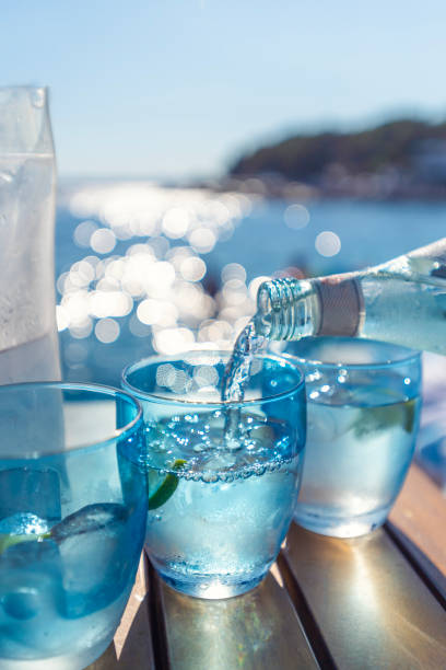 verter agua de una botella en un vaso en la playa. - water flowing water pouring ice fotografías e imágenes de stock
