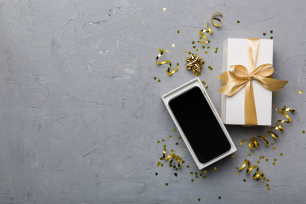 istock Opened gift box with gold ribbon and smartphone on color background, top view. Blank open box packaging mockup , Template for your design - branding mockup 1454894286