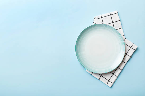 Top view on colored background empty round blue plate on tablecloth for food. Empty dish on napkin with space for your design