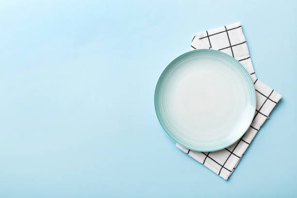 Top view on colored background empty round blue plate on tablecloth for food. Empty dish on napkin with space for your design stock photo