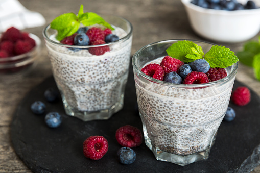 Healthy breakfast or morning with chia seeds vanilla pudding raspberry and blueberry berries on table background, vegetarian food, diet and health concept. Chia pudding with raspberry and blueberry.