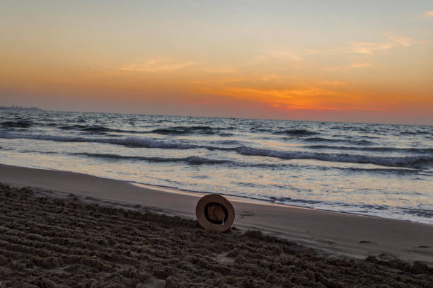 istock hat lost in the sand by the sea 1454894819