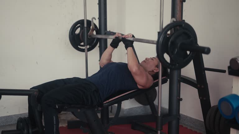 In the gym, an Asian man is using a machine to build muscle.