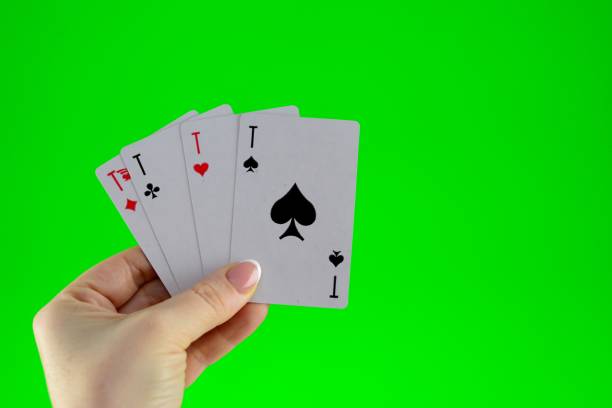 istock Hand holding four aces on a green background close-up 1454898747