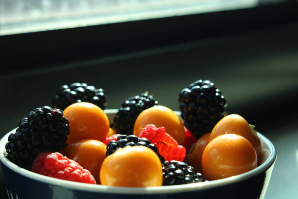 A bowl of cape gooseberries, blackberries, and raspberries