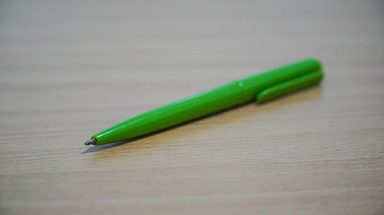 Photo of red and yellow colored wooden pencils on green background. No people are seen in frame. Shot under daylight.