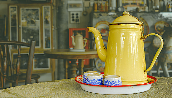 A tray of tea set on a round table consists of a teapot and 3 ceramic tea cups with isolated rustic tea house backgrounds and clipping paths.
