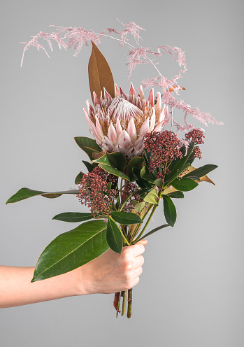 Flower bunch in hand, spring romantic gift. Posy of blossomed blooms, floral plants, leaf. High quality photo