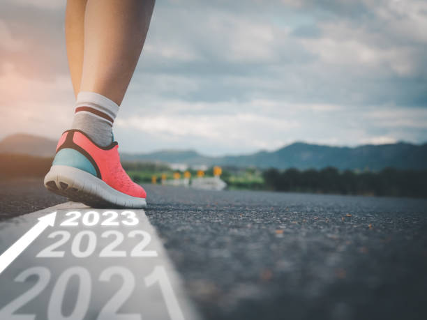 istock Step into 2023, female athlete walking on white line on road with text 1454923996