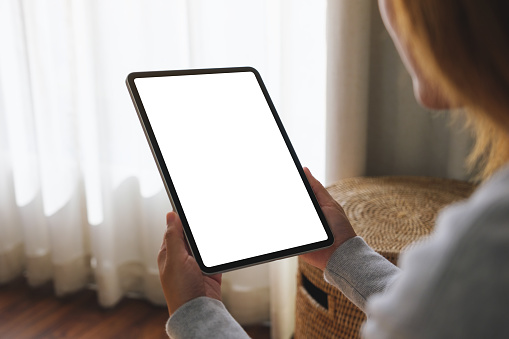 Mockup image of a woman holding digital tablet with blank desktop screen at home