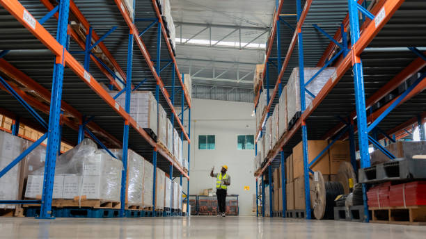 istock Portrait african black warehouse supervisor standing with digital tablet check stock in large warehouse distribution center with colleague worker in background. Business warehouse and logistic concept 1454924515