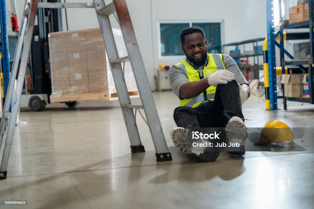 An African worker had an accident while working in a warehouse. Falling Stock Photo
