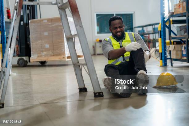 An African Worker Had An Accident While Working In A Warehouse Stock Photo - Download Image Now