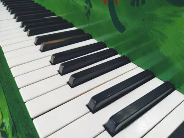 Photo of A piano or piano is a stringed percussion and keyboard musical instrument. An octave is a musical interval in which the ratio of frequencies between sounds is one to two. Green piano
