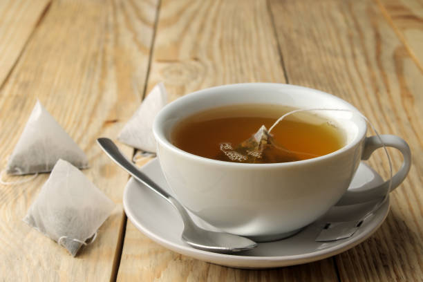 istock cup with tea and tea bag pyramid. close-up. on a wooden table. to make tea 1454927669