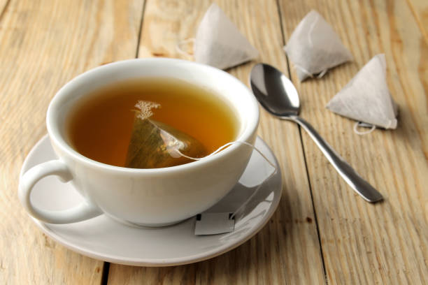 istock cup with tea and tea bag pyramid. close-up. on a wooden table. to make tea 1454927670
