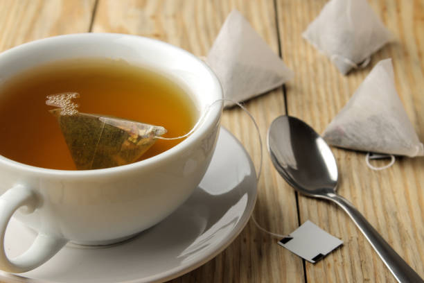 istock cup with tea and tea bag pyramid. close-up. on a wooden table. to make tea 1454927677