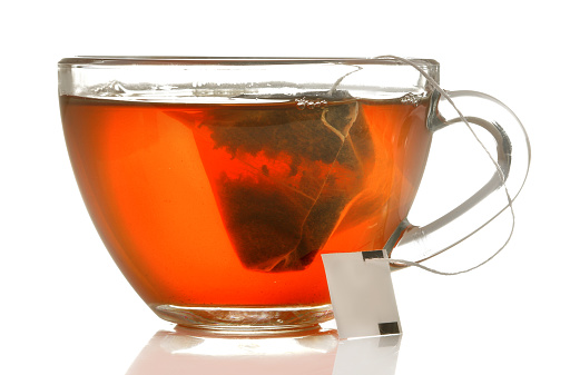 glass cup with tea and tea bag close up on white isolated background