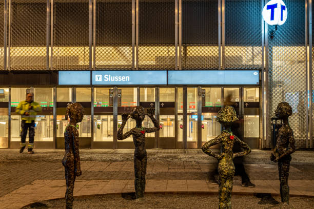 Stockholm, Sweden Dec 23, 2022  Pedestrians at the  entrance to the Slussen Metro station at night and statues by Lena Cronqvist called Six Girls from 2014.