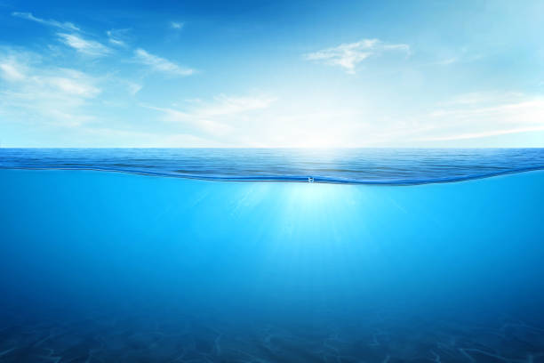 istock BLUE UNDER WATER waves and bubbles. Beautiful white clouds on blue sky over calm sea with sunlight reflection, Tranquil sea harmony of calm water surface. 1454928191