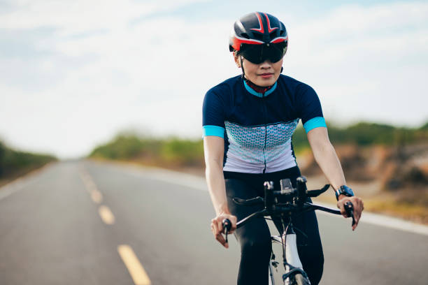 триатлонистка на велосипеде по проселочной дороге - cycling vest стоковые фото и изображения