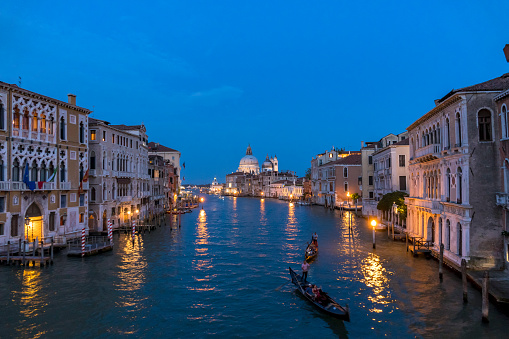 Venice, Italy - August 31st, 2019: Grand Canal, old buildings and Basilica di Santa Maria della Salute in Venice, Italy at dusk
