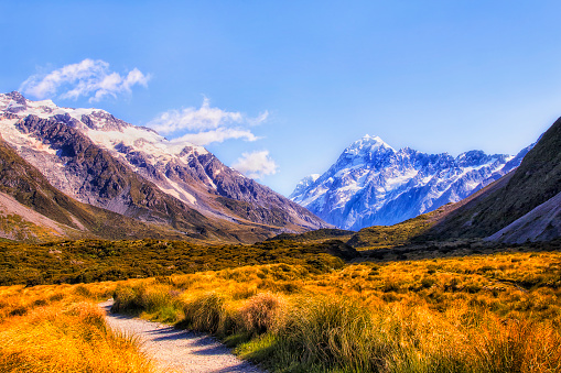 Walking track in Hooker valley to distant Mt Cook in snowcapped alpine mountains of New Zealand.