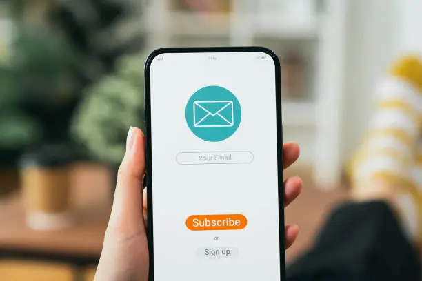 Photo of Hand holding smartphone and shows a digital screen of subscribe email notifications or sign up.