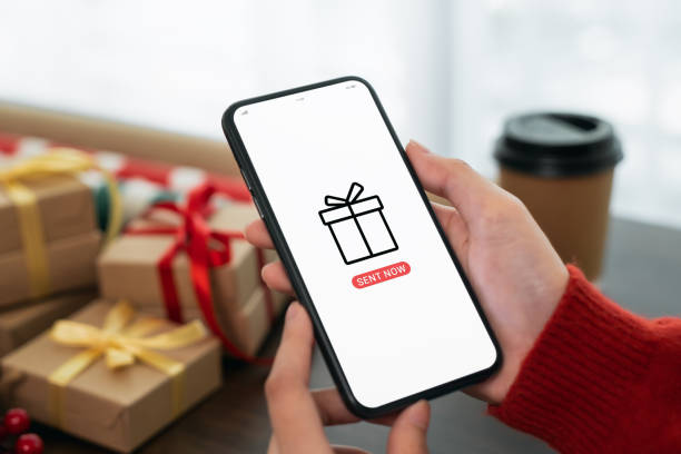 istock Hand using smartphone with sent gift to mobile application and festive decorations on the black background. 1454937343