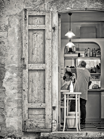 The Abruzzo region in Italy on May  31, 2022:   Customer in a rustic barber shop in the Abruzzo town of Scanno in Italy