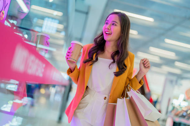 belle femme asiatique fille tient des sacs à provisions et une boisson au café, marche et joyeuse profiter de sourire tout en faisant du shopping dans les centres commerciaux de grands magasins de charme femmes bonheur lèche-vitrine - disposable cup coffee shopping friendship photos et images de collection