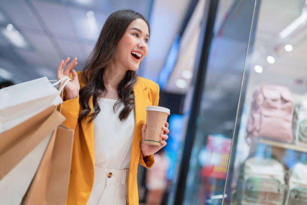 belle femme asiatique fille tient des sacs à provisions et une boisson au café, marche et joyeuse profiter de sourire tout en faisant du shopping dans les centres commerciaux de grands magasins de charme femmes bonheur lèche-vitrine - disposable cup coffee shopping friendship photos et images de collection