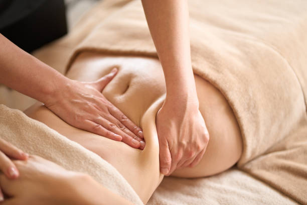 une femme recevant un massage du ventre dans un salon de beauté - abdomen women massaging human hand photos et images de collection