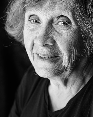 Portrait of senior smiling caucasian woman on black background. Close up, Black and white