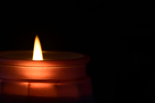 A bright candle light on dark background