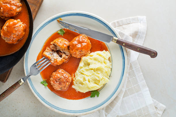 Meatballs in tomato sauce with mashed patatoes Fried meatballs braised in tomato sauce served with mashed potatoes on white table. Eating Beef roasted meatballs in tomato sauce. braising pan stock pictures, royalty-free photos & images