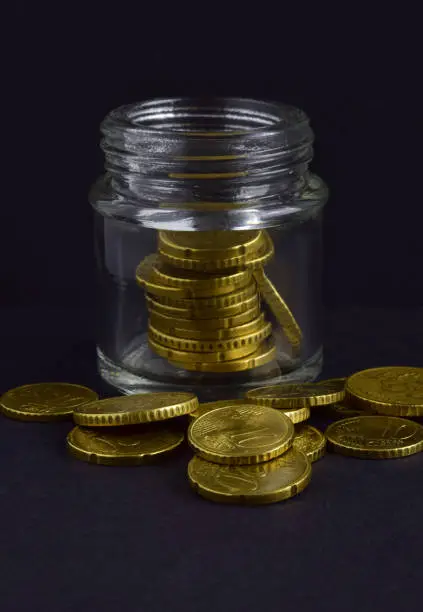 The euro coins scattered and in the glass jar isolated on a black background