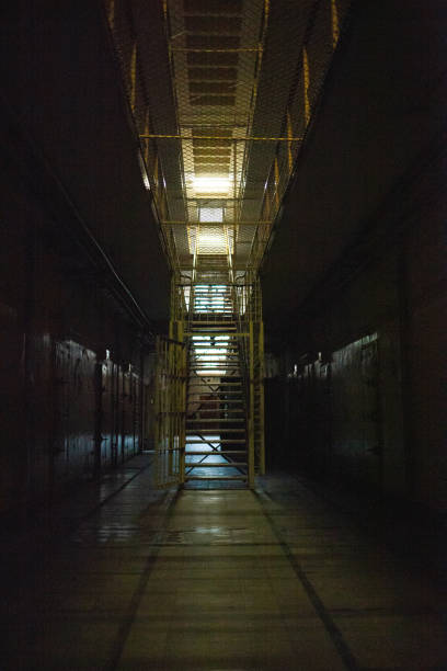 istock Dark corridor and metal stairs in an old prison 1454957868