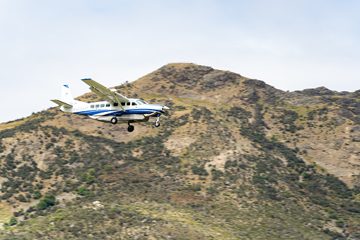 Queenstown, New Zealand -December, 2022: an airplane is passing the mountain to land at the airport.