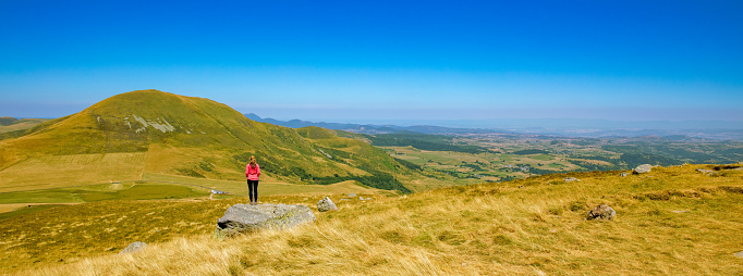Hiker woman looking at panoramic landscape view- Auvergne, Cantal in France