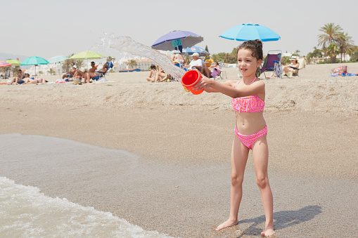 Girl in a pink bikini playing happily on the shore of the beach on a sunny summer day, Vera, Spain