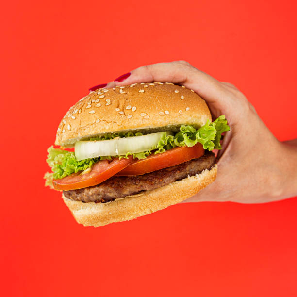 istock Hand holding a classic grilled hamburger 1454959441