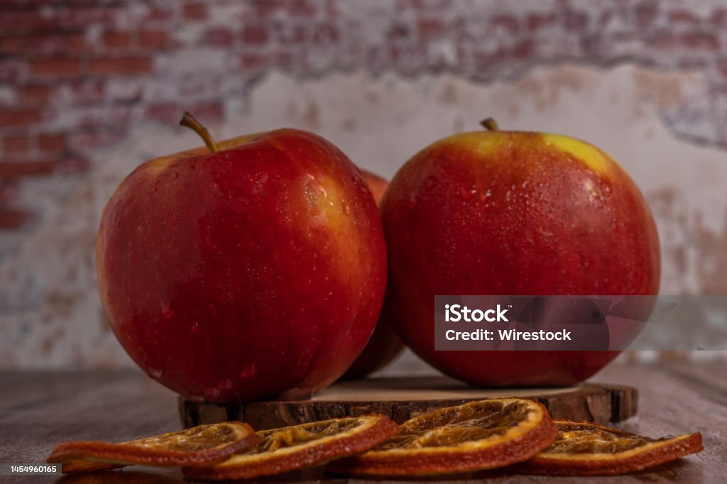 close-up of three fresh red apples with water drops close-up of three fresh red apples with drops of water on a slice of wood Agriculture Stock Photo