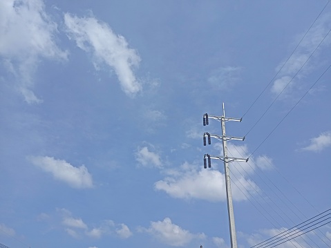 Electric pole connect to the high voltage electric wires on blue sky and cloud background