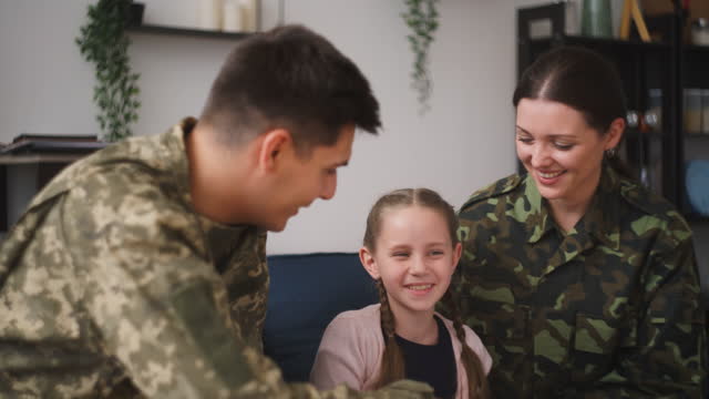Pretty little girl having fun with loving military parents, happy family smiling