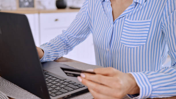 istock Female working on a laptop and holding a card 1454963344