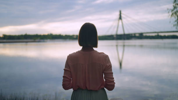 istock Back view of a female admiring a lake view 1454963347